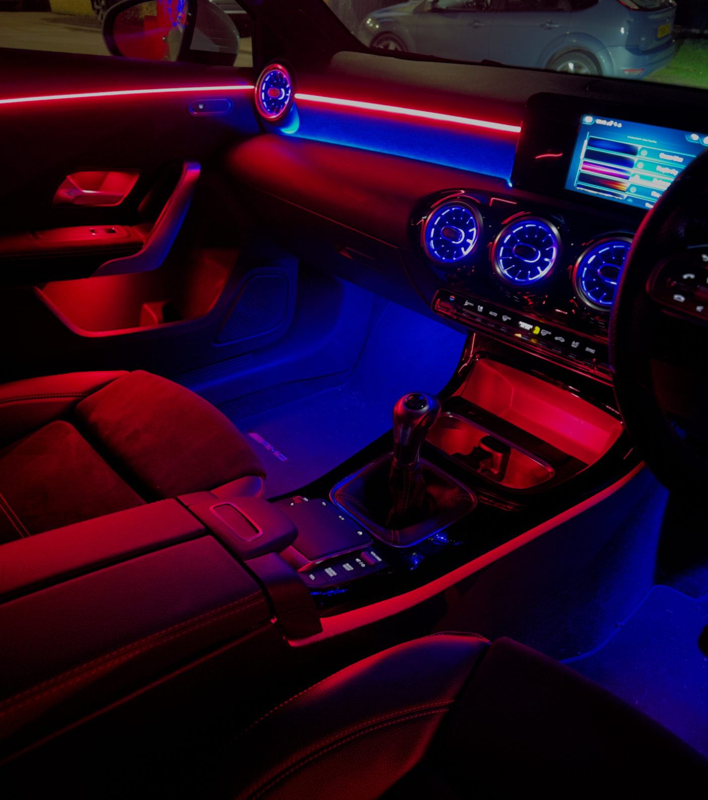 Vibrant red and blue LED car interior lighting by Two Shades London, featuring digital gauges and premium seating.